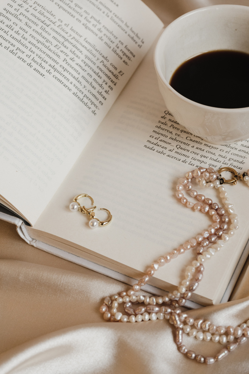 Pearl Necklace and Earrings with Cup of Coffee on Book